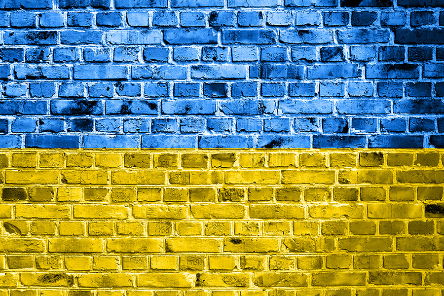 National flag of Ukraine painted on a brick wall. Banner on old brick wall background in cracks blue and yellow colors. The concept of relations between countries - no war between Ukraine and Russia.